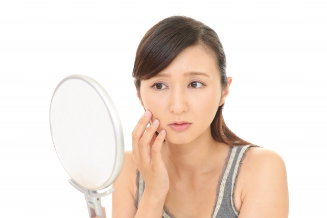鏡を見ながら顔の状態を確認している女性
