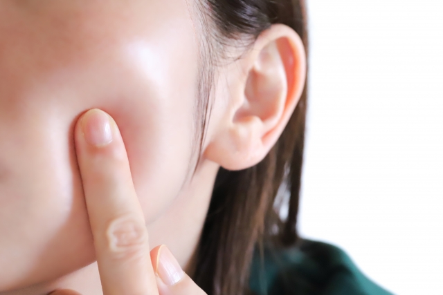 指で頬を押しながら表情筋の弾力を確かめる様子